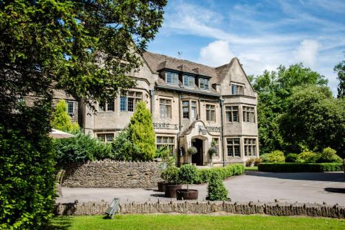 a large stone house with a stone wall at The Hare & Hounds Hotel in Tetbury