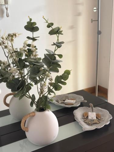 two white vases with flowers in them on a table at Apartamento Baztan Berri in Elizondo