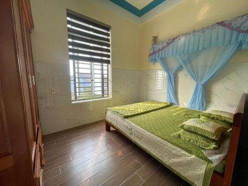 a bedroom with a bed with a blue curtain and a window at Memory Homestay Ông Chung in Lệ Thủy