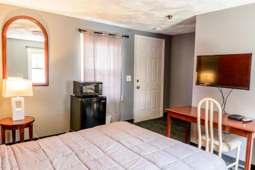 福克斯伯勒的住宿－雷德福克斯汽車旅館，一间卧室配有一张床、一张书桌和一台电视