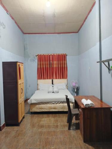 a bedroom with a bed and a desk and a desk at Keluncing Field Homestay in Tetebatu