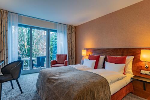 a hotel room with a bed and a large window at Wellings Romantik Hotel zur Linde in Moers
