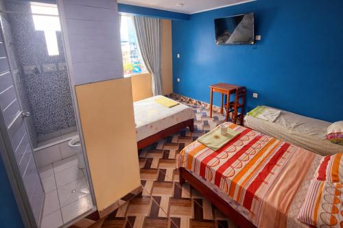 a small room with two beds and a shower at HOSPEDAJE EL CANTARO II in Tingo María