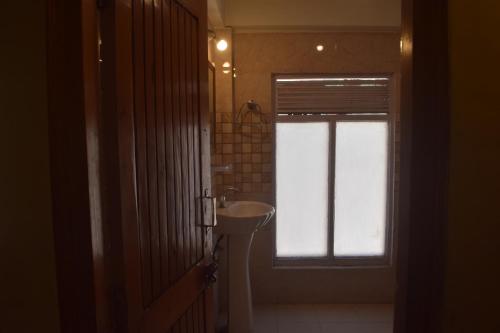 a bathroom with a sink and a window at Hotel Tridev Manali in Manāli