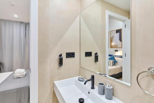 a white bathroom with a sink and a mirror at Sant Adrià Urban Suites by gaiarooms in Badalona
