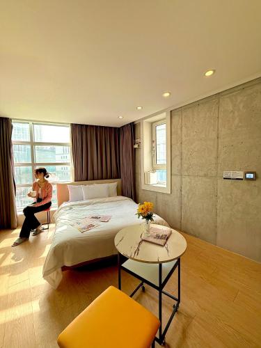 a woman sitting on a bed in a room at Connected Hotel Guro in Seoul