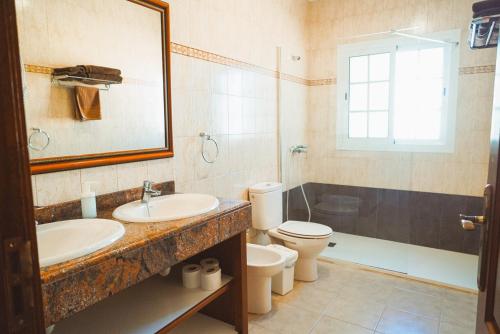 a bathroom with a sink and a toilet and a mirror at Apartamentos Graciosamar in Caleta de Sebo