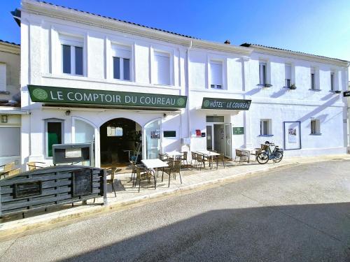 a white building with tables and chairs in front of it at Hotel Le Coureau in Saint-Trojan-les-Bains