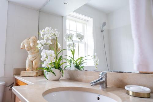 a bathroom with a sink and a mirror and flowers at Quinta das Mineirinhas in Vila Nova de Cerveira