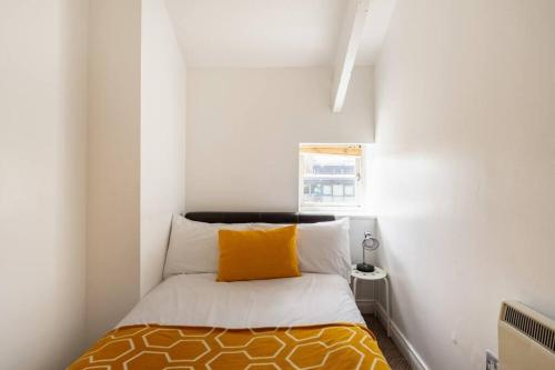 a small room with a bed with a yellow pillow at Newcastle City Centre Apartment in Newcastle upon Tyne