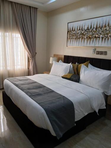 a bedroom with a large white bed with a window at Stallion Luxury Suites in Ado