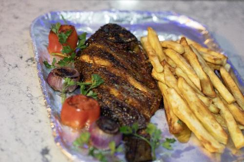 a plate of food with steak and french fries at Stallion Luxury Suites in Ado