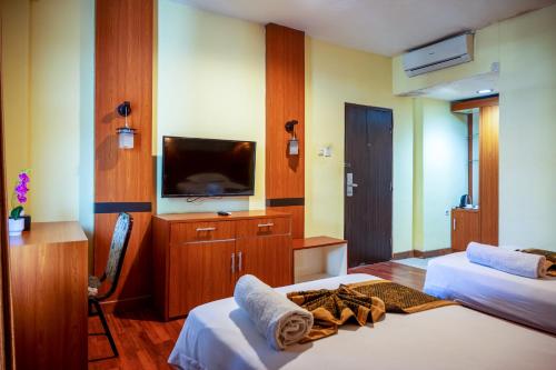 a hotel room with two beds and a flat screen tv at Tripletree Stefani Hotel in Pekanbaru