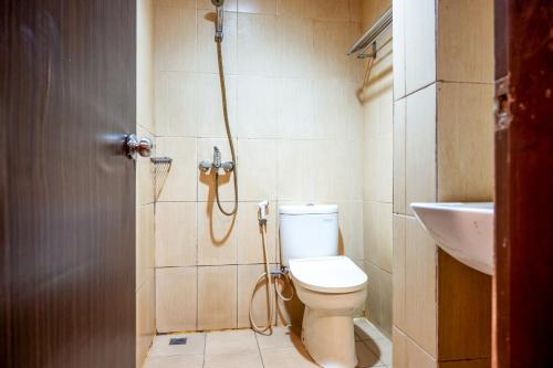 a bathroom with a shower and a toilet and a sink at Tripletree Stefani Hotel in Pekanbaru