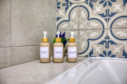 three bottles ofodorizers sitting next to a bath tub at Valletta Marina View - Seafront Apartment in Tal-Pietà