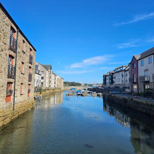 a river in a city with buildings and boats at Penryn Quayside Apartment – 1-bed, Fully Equipped Waterside base in Penryn
