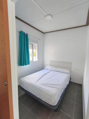 a bed in a room with a green curtain at Camping Barraquetes in Sueca