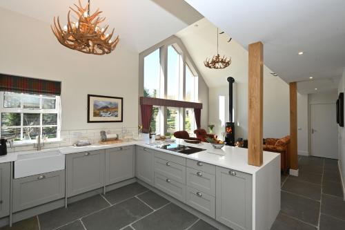 a large kitchen with white cabinets and windows at Kennels Cottage in Buchanty