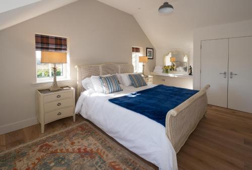a bedroom with a large bed with a blue blanket at Kennels Cottage in Buchanty