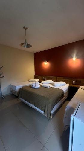 a bedroom with two beds and a red wall at Pousada Villa da Serra in Brumadinho