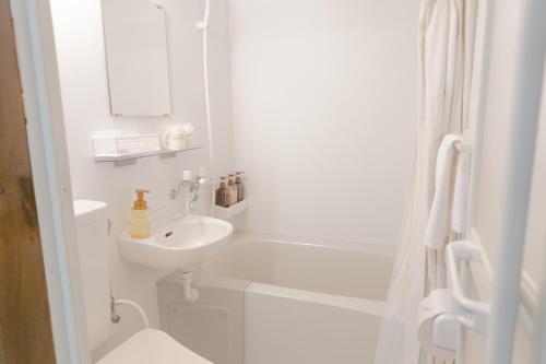 a white bathroom with a sink and a toilet at 還元ホテル 名護東江 in Nago