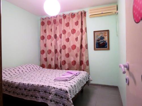 uma pequena cama num quarto com uma cortina rosa em 2 bedroom apartment in Atlit, Haifa district em Atlit