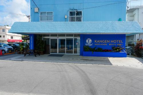 a blue building with a blue roof on a street at 還元ホテル 名護東江 in Nago