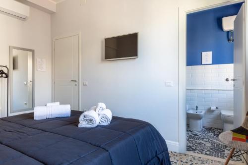 a bedroom with a blue bed and a tv on the wall at Lorixedda Rooms in Quartu SantʼElena