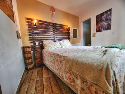 a bedroom with a large bed with a wooden headboard at Suítes Aconchego - Pousada Rústica & Café da Manhã Especial in Lençóis