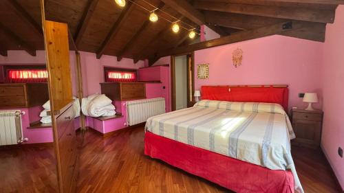 a bedroom with a bed and pink walls and wooden floors at Casa Zia Pia in Baveno
