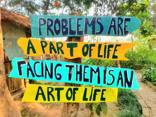a sign that says problems are a part of life and art of life at Pemsee's Tree Town - Eco Treehouse Hostel in Sauraha