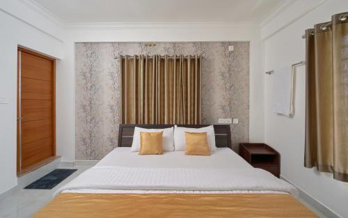 a bedroom with a large white bed with yellow pillows at BHRS Residency in Munnar