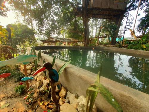 a bird is standing next to a pool of water at Pemsee's Tree Town - Eco Treehouse Hostel in Sauraha
