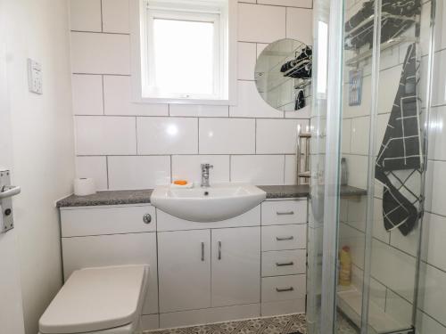 a white bathroom with a sink and a shower at 90 Bay View in New Romney