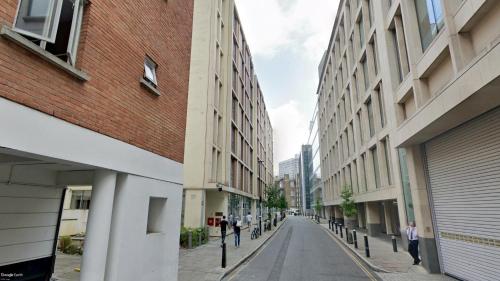 a city street with buildings and people walking down the street at The Lambs Passage Executive Apartment in London