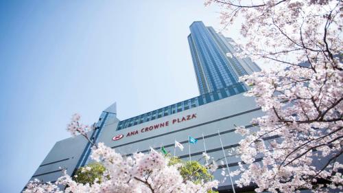 a building with a sign on it withakura trees in front of it at ANA Crowne Plaza Kobe by IHG in Kobe