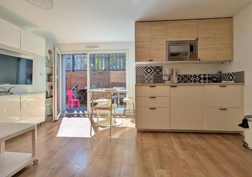 a kitchen with white cabinets and a dining room with a table at Aux cigognes de Blotzheim in Blotzheim