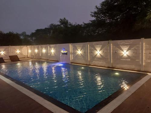 a swimming pool with lights in a backyard at night at Amigos Farm in Lucknow