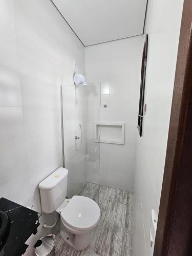 a white bathroom with a toilet and a shower at Schulz Pousada in Joinville