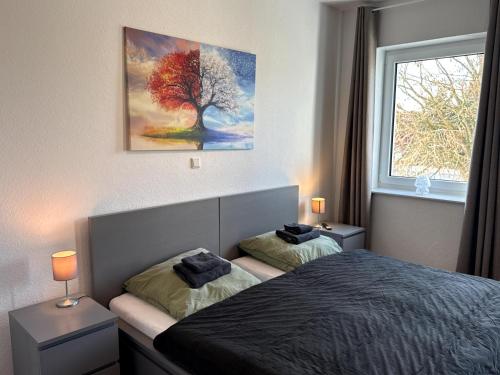 a bedroom with a bed and a tree painting on the wall at Apartment Landblick in Bohmte