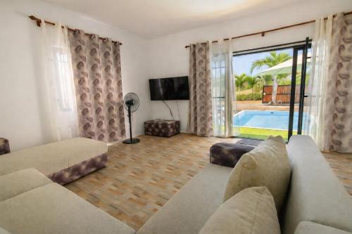 a living room with a couch and a tv and a pool at Hope Villa in Calodyne