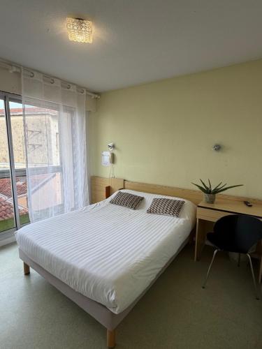 a bedroom with a bed and a desk and a window at Hotel Bains Sarrailh in Dax