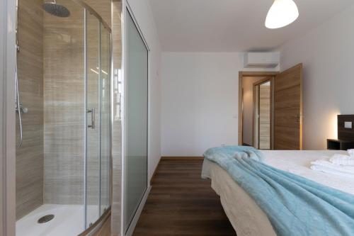 a bathroom with a shower and a bed and a tub at Trajadinha do Lima Apart in Ponte de Lima