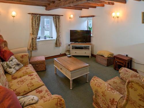a living room with couches and a flat screen tv at Howards End in Middleton on the Hill