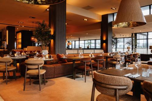 a restaurant with tables and chairs and a couch at Van der Valk Hotel Oostzaan - Amsterdam in Oostzaan