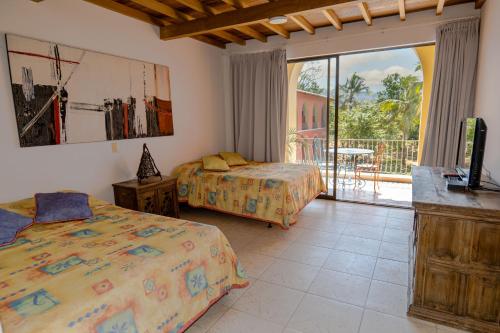 a bedroom with two beds and a balcony at Hotel y Spa Santa Fe Colonial in Santa Fe de Antioquia
