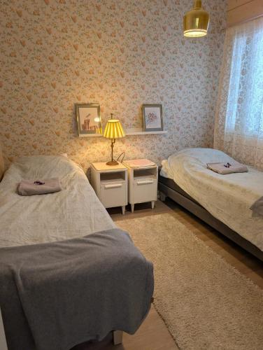 a bedroom with two beds and a lamp and a window at Lake Norva Lodge in Saarenkylä