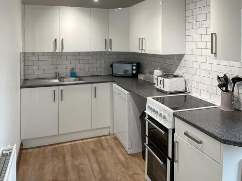 a kitchen with white cabinets and a stove top oven at Mistletoe Cottage - Uk50581 in Burnham on Sea