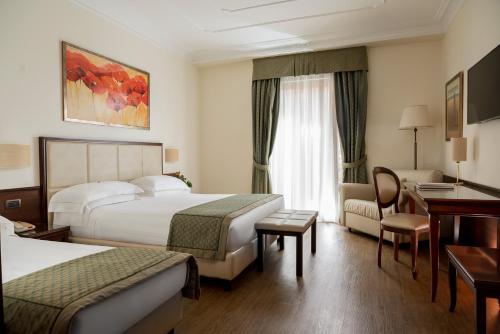 a hotel room with two beds and a desk at Hotel Athena in Siena