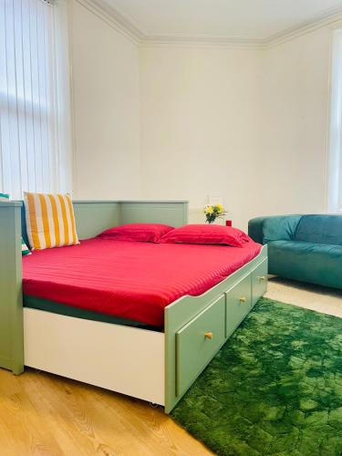 a bedroom with a bed with red sheets and a couch at Cozy Cottage in Liverpool